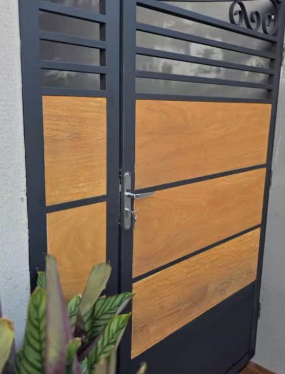 Porta de entrada em metal preto com painéis de madeira