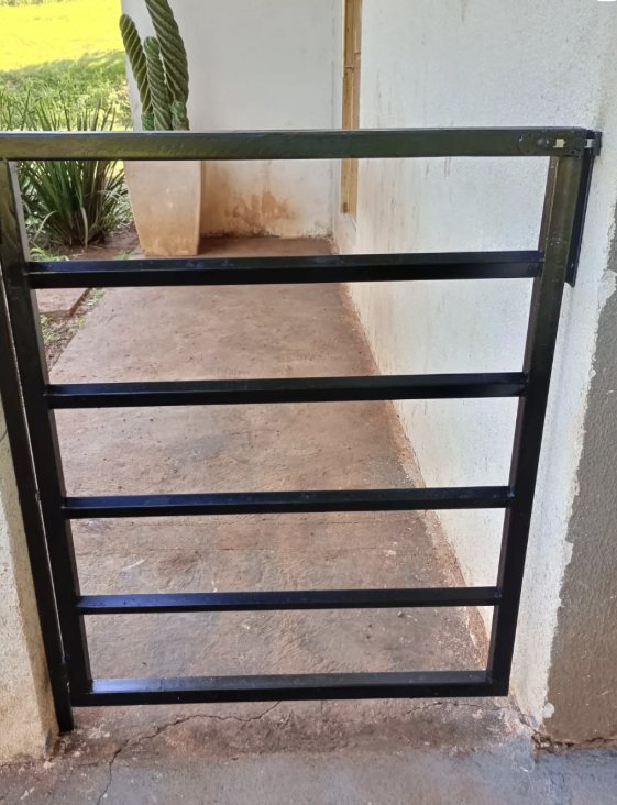 Portãozinho de grade em metal preto instalado em passagem lateral